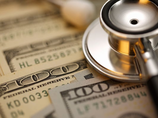 Stethoscope sitting on top of 100 dollar bills